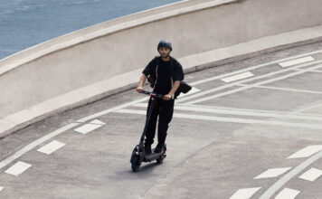 A man zooming down a road on a Segway Max G3 electric scooter