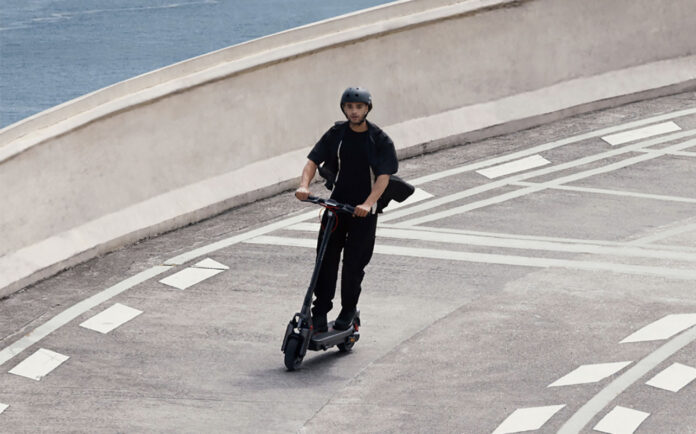 A man zooming down a road on a Segway Max G3 electric scooter