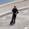A man zooming down a road on a Segway Max G3 electric scooter
