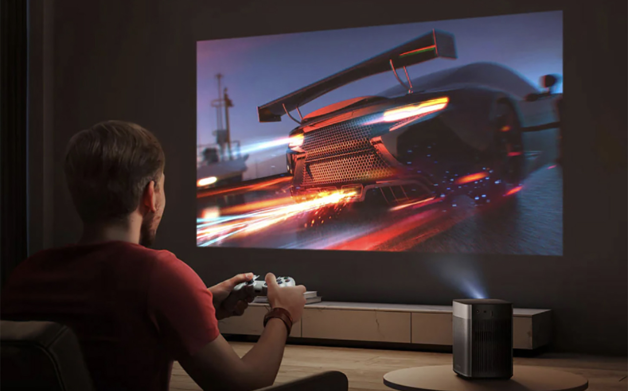 Un homme jouant à un jeu vidéo sur un grand écran à l'aide d'un projecteur Halo Plus de Xgimi.