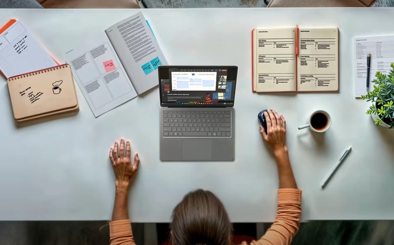 Woman with AI laptop on desk surrounded by tasks to be done.