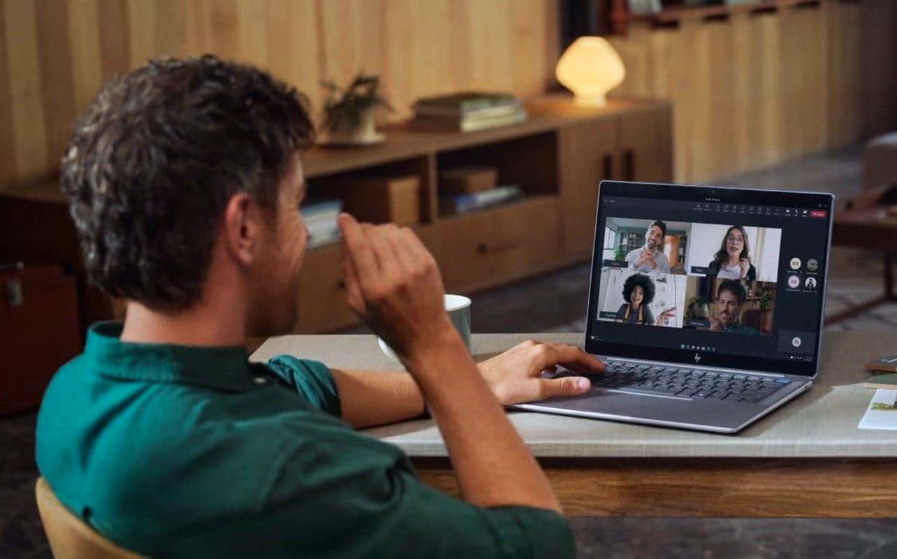 Man on video call with others on AI laptop.