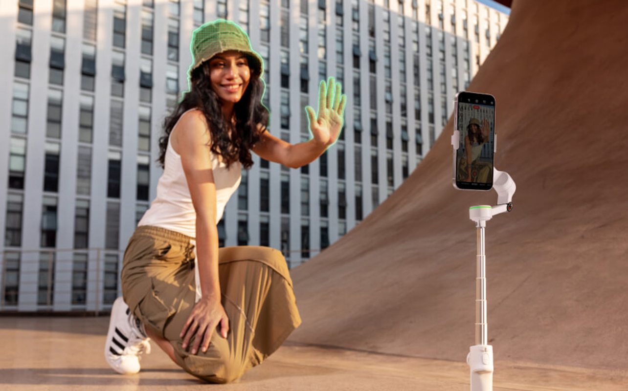 Woman gesturing at smartphone mounted on gimbal.
