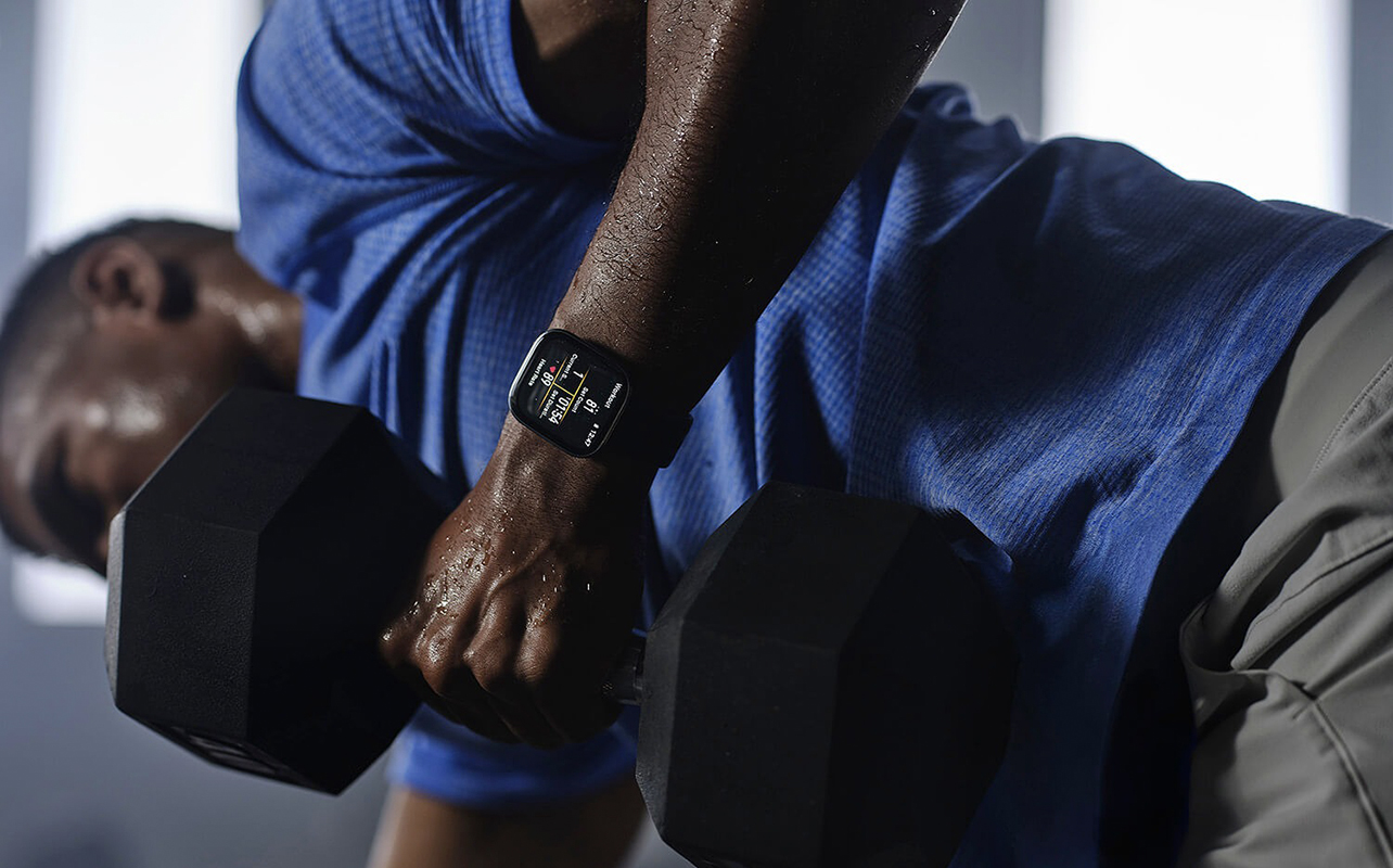 Un homme qui soulève des poids en portant la montre intelligente Bip 6 d'Amazfit. 