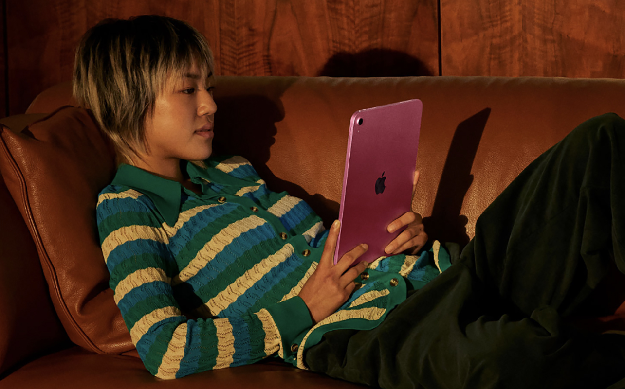 Une femme allongée sur un canapé avec un Apple iPad A16.