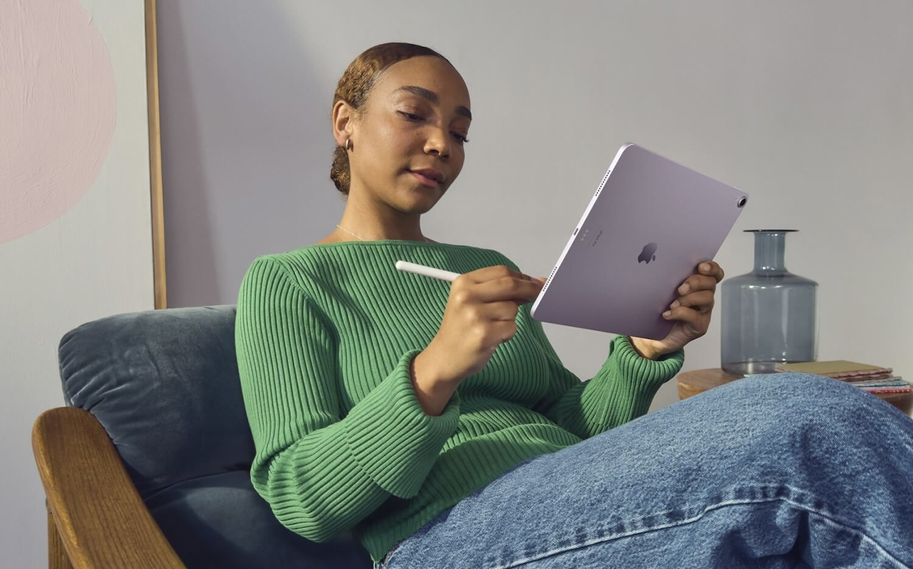 Une femme assise, se relaxant avec un Apple iPad Mini.