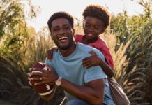 father and son playing baseball in a field. The dad is wearing a Citizen stylish watch.