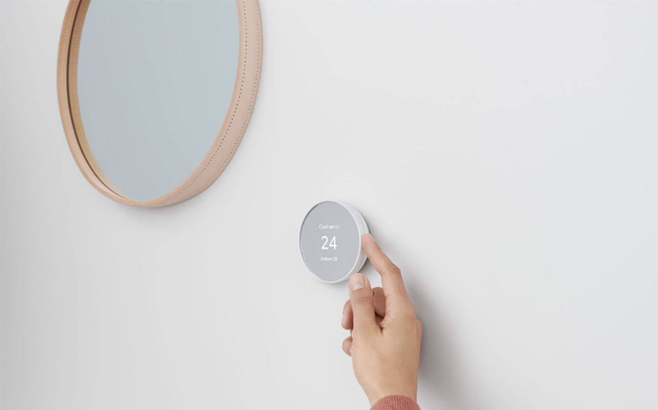 Un doigt ajustant un thermostat intelligent Google Nest.