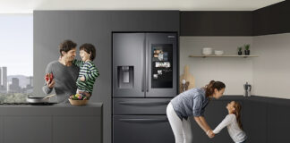 A family in the kitchen with the Samsung Family Hub fridge behind them.