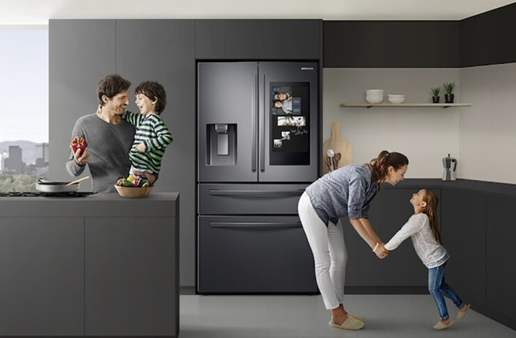 A family in the kitchen with the Samsung Family Hub fridge behind them.