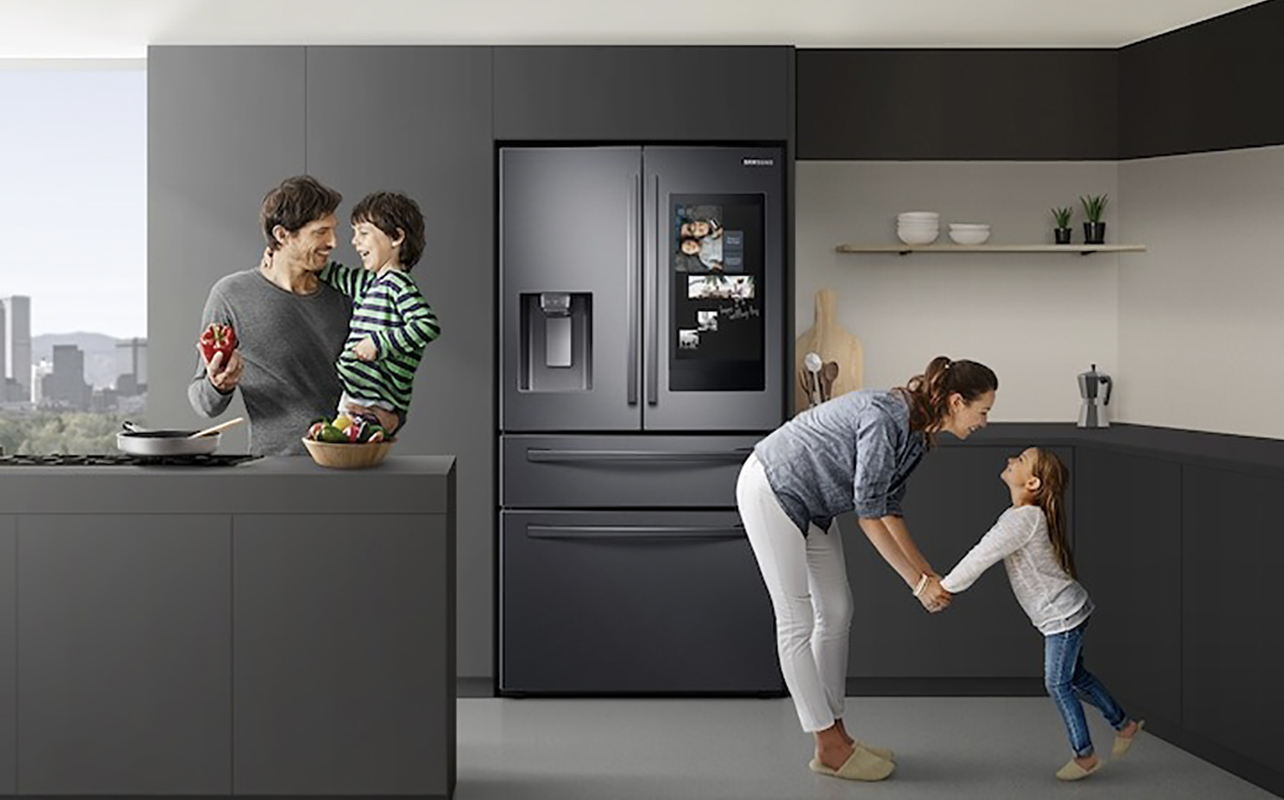 A family in the kitchen with the Samsung Family Hub fridge behind them.