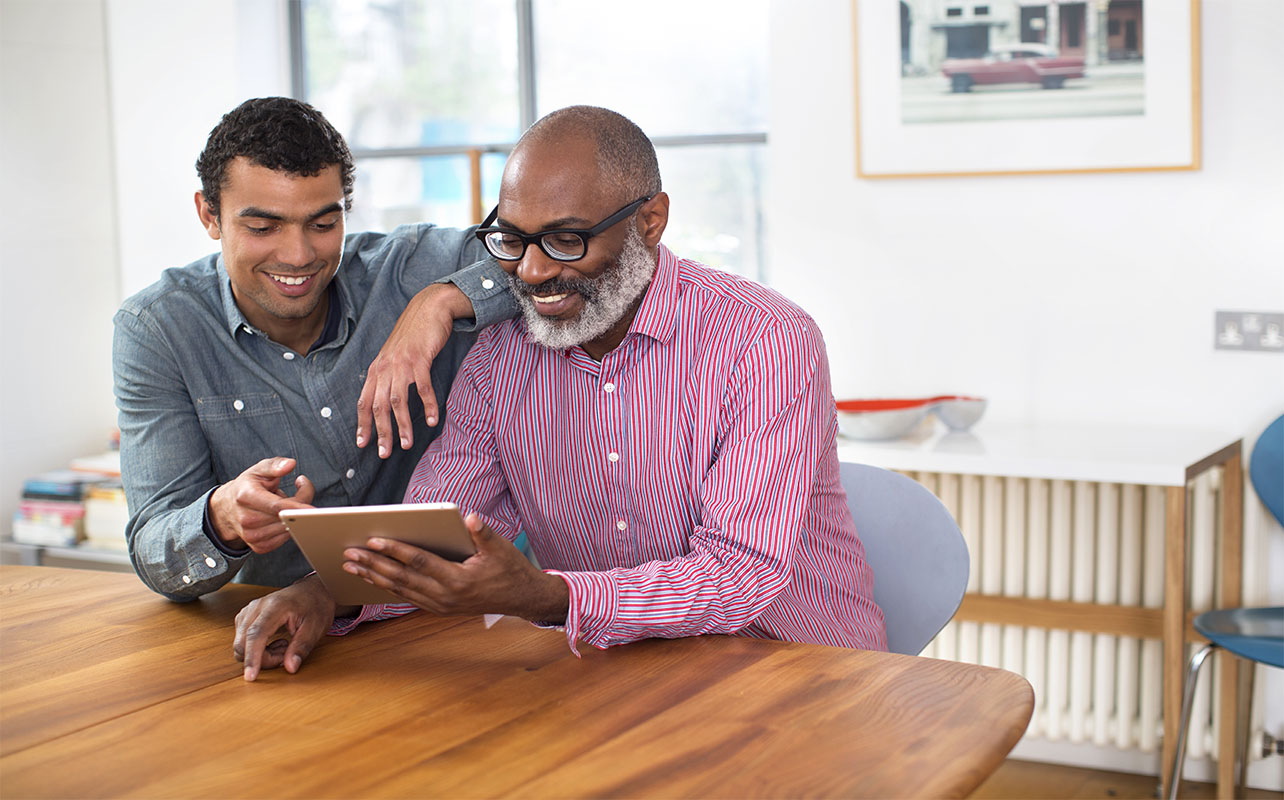 father's day gift ideas - a son teaching and showing his dad how to use the new tablet