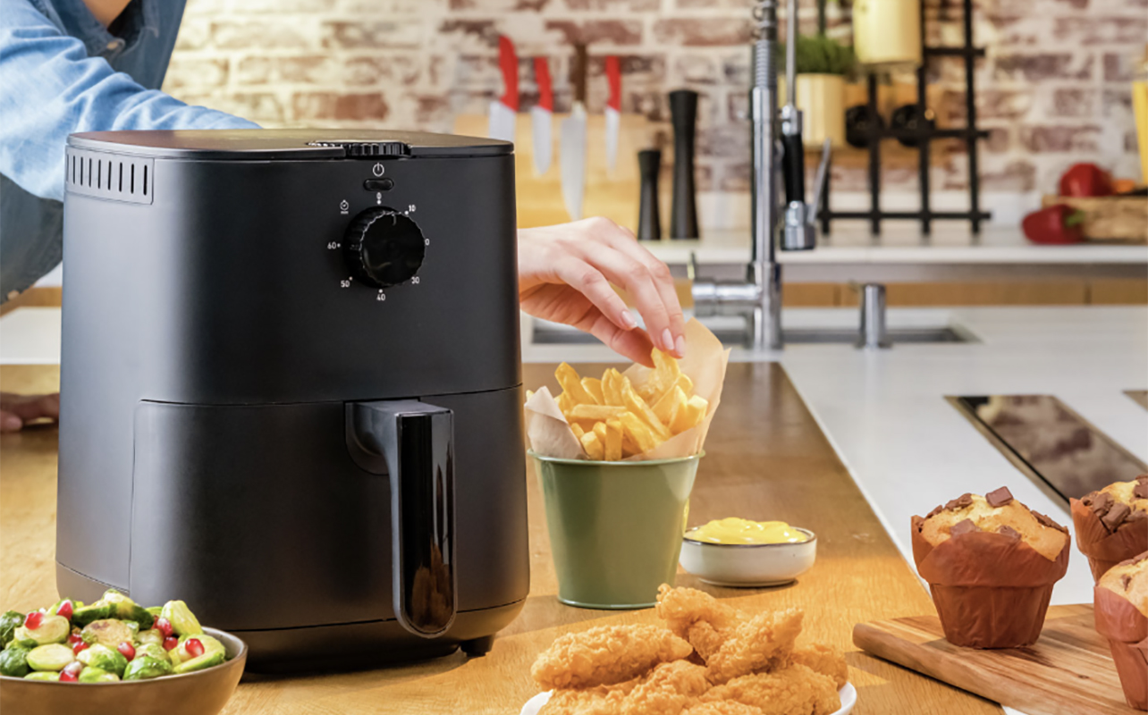 A T-Fal Easy Fry Essential air fryer with various dishes in front of it.