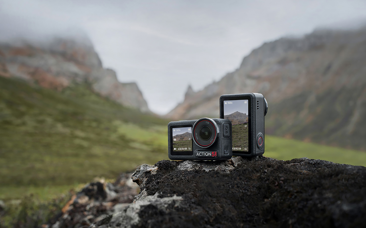 Action camera positioned against a scenic mountain backdrop with rugged peaks.