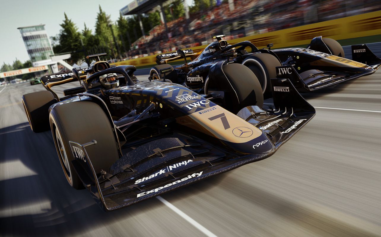 Une scène de course intense tirée du film F1 à venir. L'image montre deux voitures de F1 APXGP, peintes en noir et or, qui s'affrontent côte à côte sur un circuit à grande vitesse. Le gros plan met en valeur le design élégant des voitures et leur mouvement dynamique. L'arrière-plan est flou, ce qui traduit le frisson et la vitesse de la compétition sur la piste.