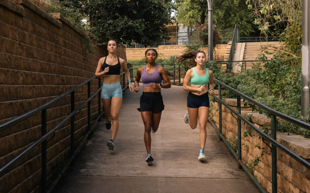 Three women running wearing Garmin Forerunner smartwatches.