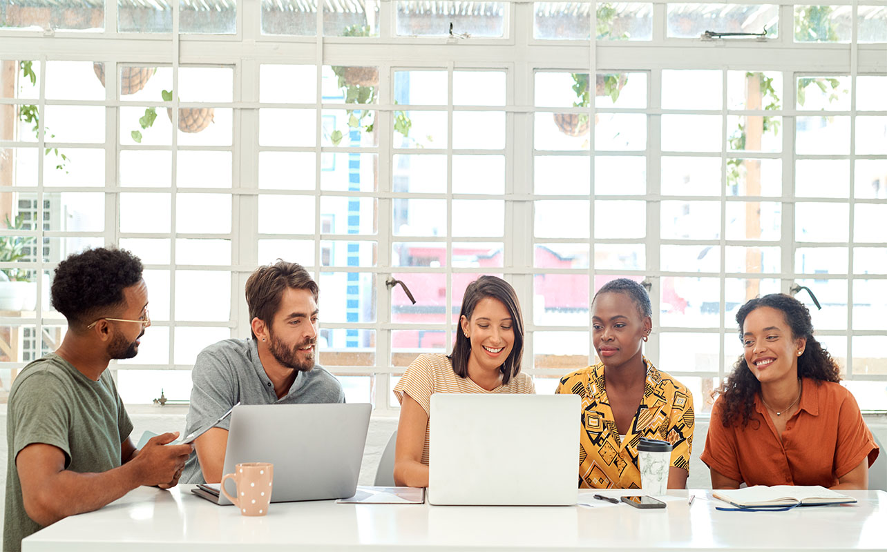 A group of businesspeople working together on a laptop in an office