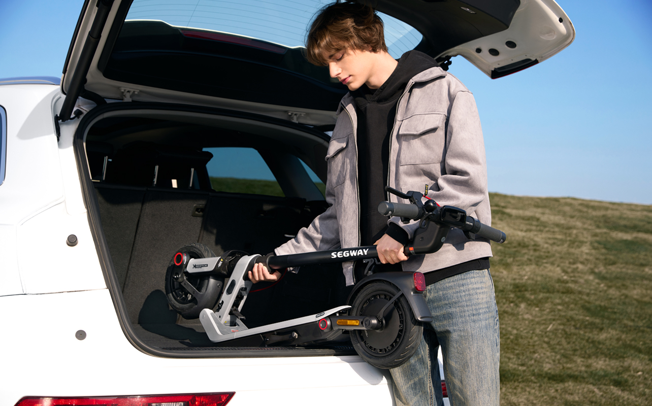 Man folding Segway E3 electric scooter in car trunk.