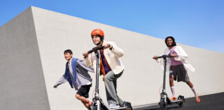 Three kids riding on Segway E3 electric scooters outside.