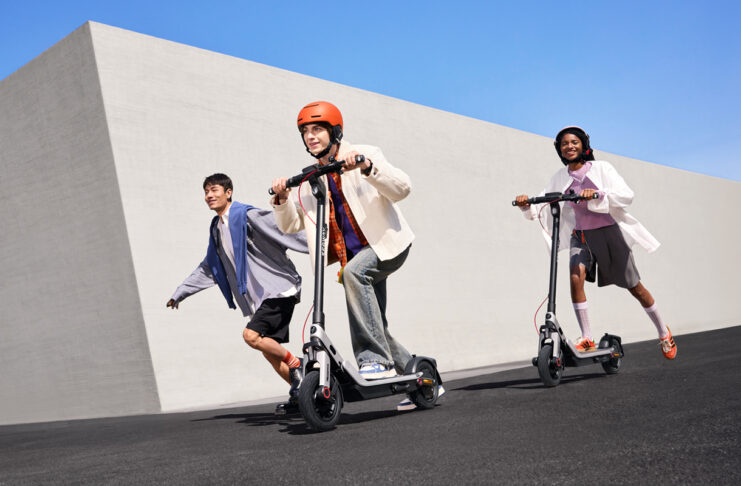 Three kids riding on Segway E3 electric scooters outside.