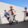 Three kids riding on Segway E3 electric scooters outside.