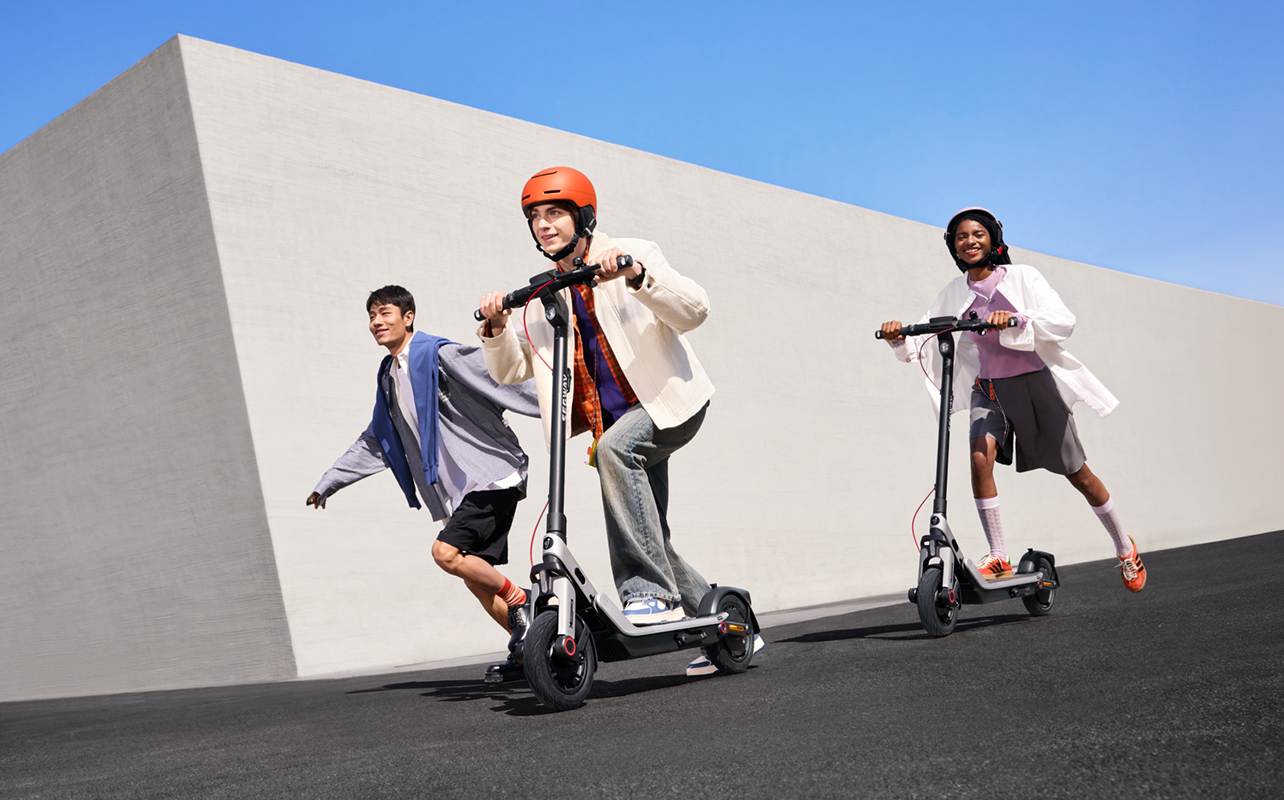 Three kids riding on Segway E3 electric scooters outside.