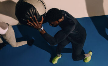 A man holding a ball above his head with an Apple Watch on.