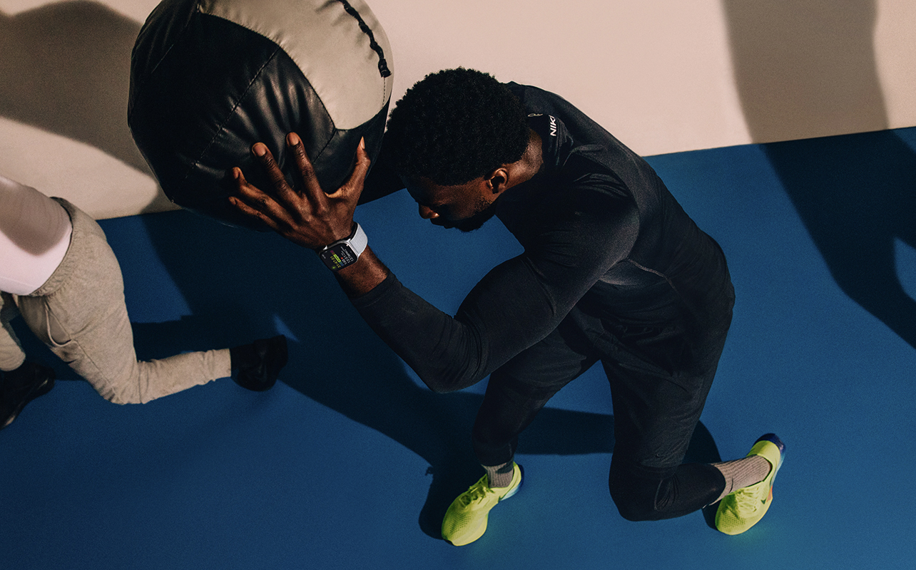 A man holding a ball above his head with an Apple Watch on.