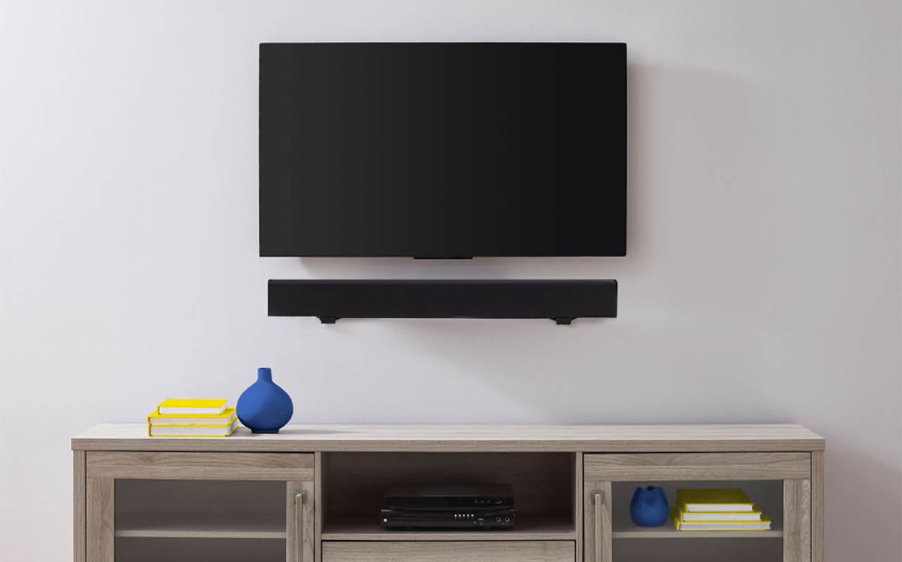 A TV with a sound bar underneath mounted with a Best Buy Essentials soundbar.