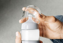 A hand opening the lid of the Ember baby bottle warmer
