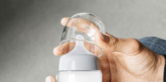 A hand opening the lid of the Ember baby bottle warmer