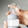A hand opening the lid of the Ember baby bottle warmer