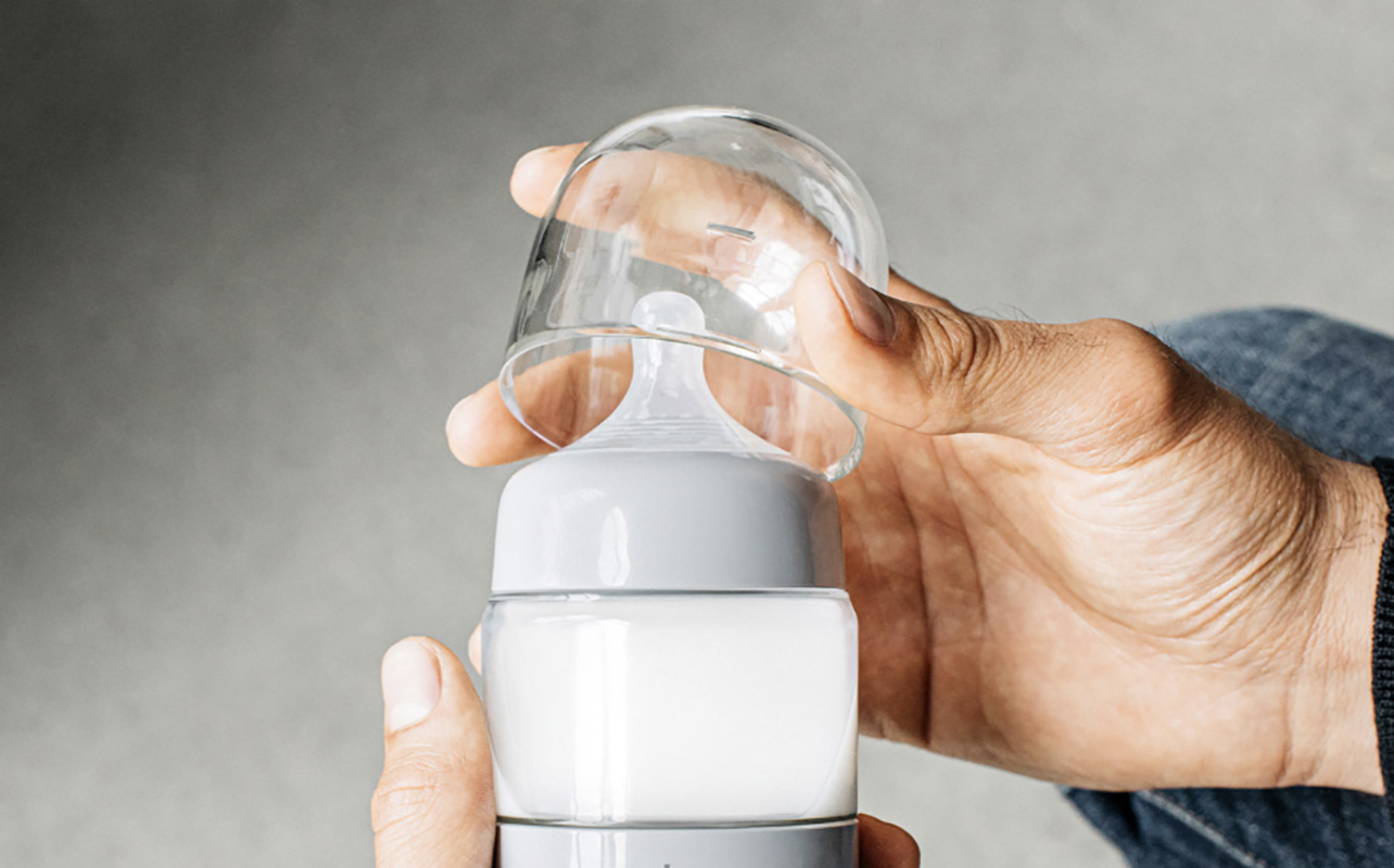 A hand opening the lid of the Ember baby bottle warmer