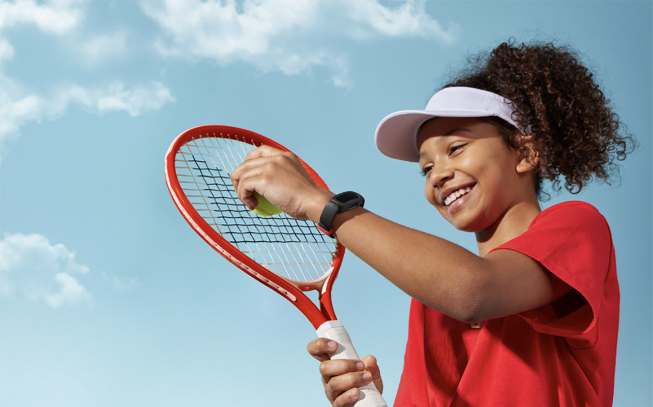 A young girl playing tennis while wearing a Fitbit Ace 3.