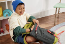 A young boy packing his schoolbag while wearing the Fitbit Ace 3 smartwatch.