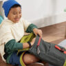 A young boy packing his schoolbag while wearing the Fitbit Ace 3 smartwatch.
