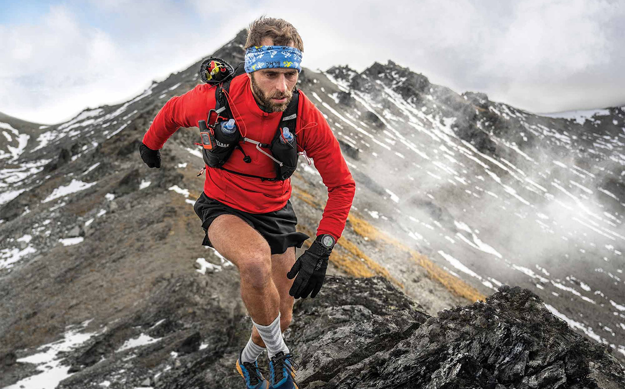A man hiking through the mountains while wearing the Garmin Enduro 3 smartwatch.