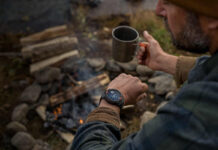 A man looking at the Garmin Instinct Solar 3 on his wrist while camping.