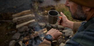 A man looking at the Garmin Instinct Solar 3 on his wrist while camping.