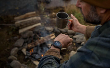 A man looking at the Garmin Instinct Solar 3 on his wrist while camping.