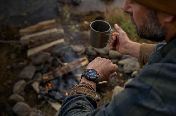 A man looking at the Garmin Instinct Solar 3 on his wrist while camping.