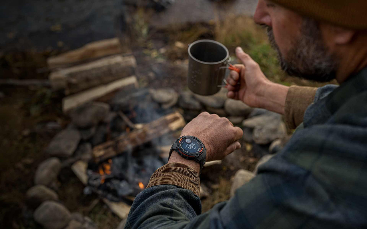 A man looking at the Garmin Instinct Solar 3 on his wrist while camping.