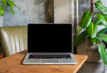 Laptop computer blank screen on table in cafe background. Laptop with blank screen on table of coffee shop blur background