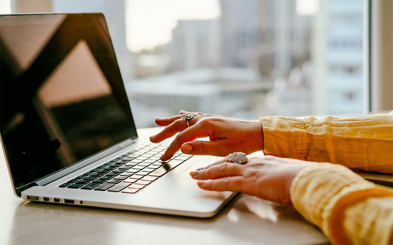 Portrait of a woman typing on laptop.
