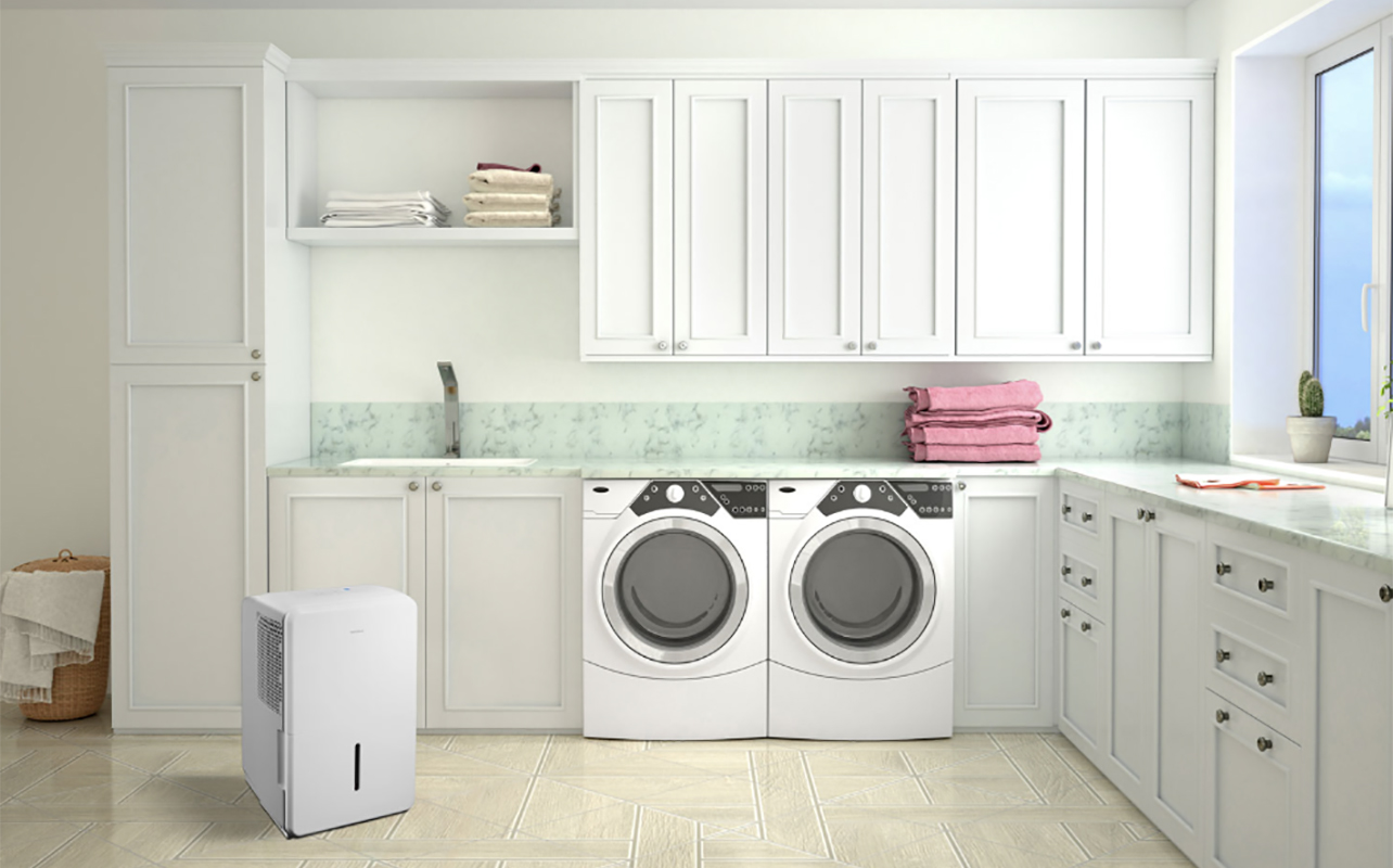 A laundry room with an Insignia dehumidifier in the left corner.