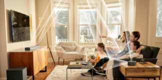 A family watching TV with the JBL Bar 820 9-channel sound bar mounted and lines showing the different channels and how and where they send audio.