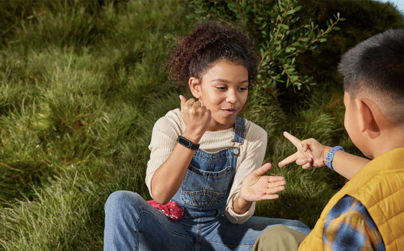 A young girl and boy playing outside with the Fitbit Ace 3