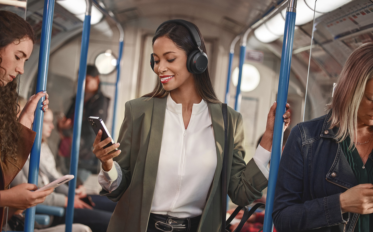 Woman on subway train with active noise cancellation headphones.