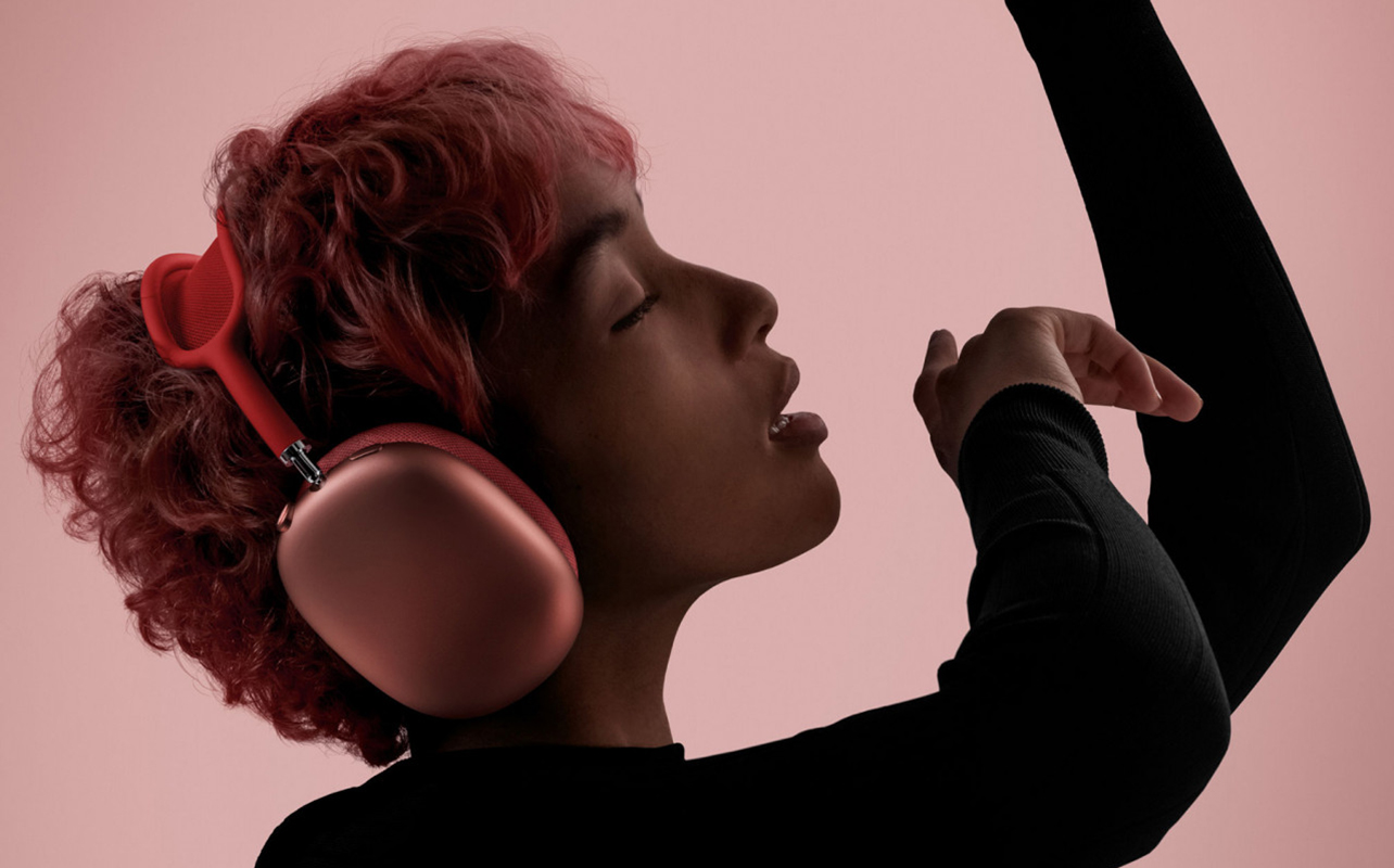 Woman with pink hair wearing pink Apple AirPods Max headphones.