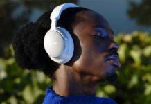 Man wearing white Bose QuietComfort Ultra headphones outside.